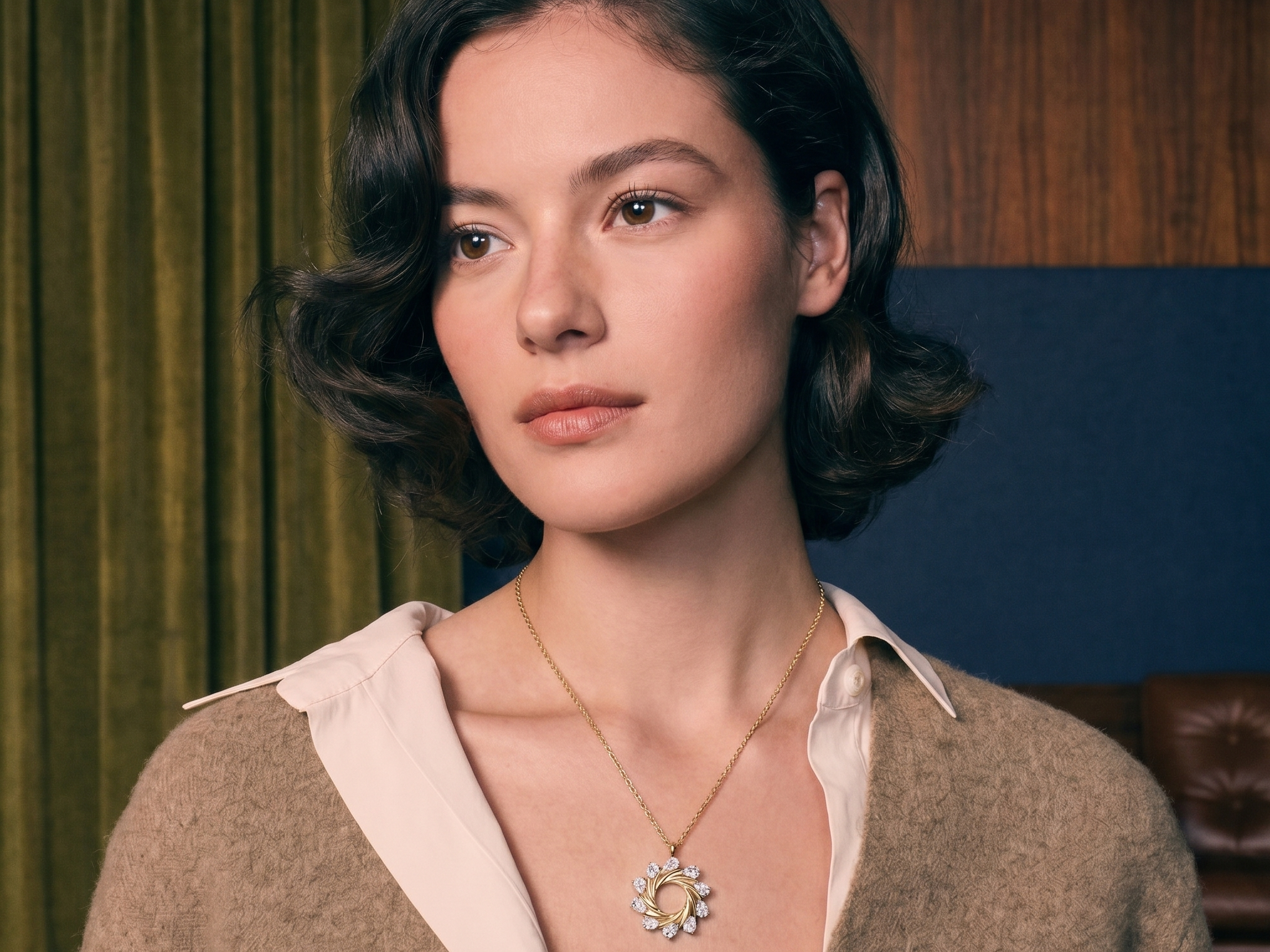 Diamond charm necklace layered on a woman's decolletage in solid gold, soft natural light