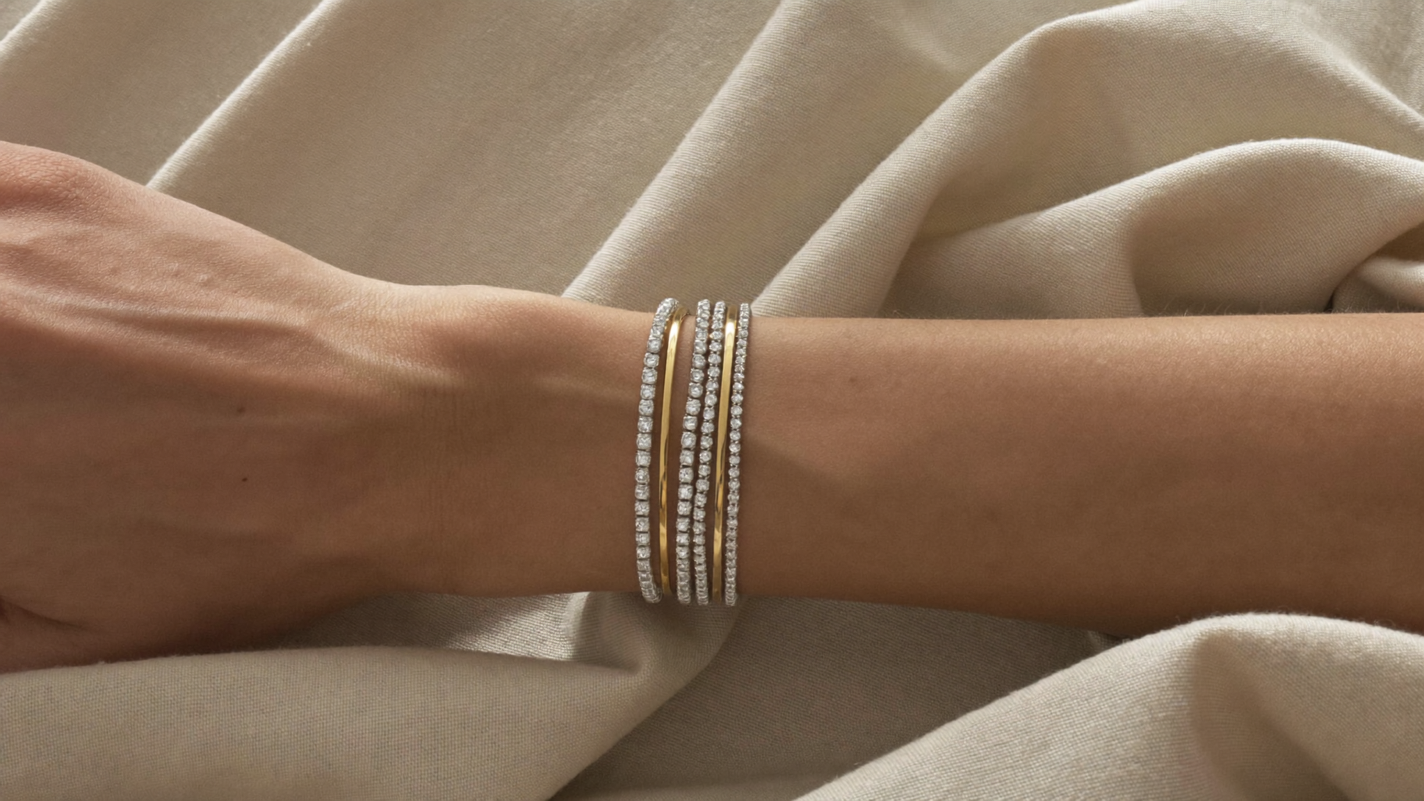 Stacked lab-grown diamond tennis bracelets and thin gold bangles on a woman's wrist, a 2026 bracelet stack