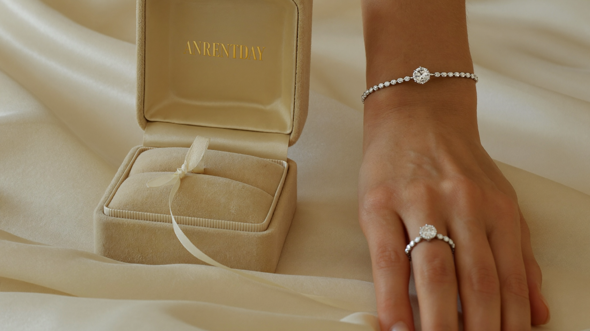 Diamond anniversary gifts: a diamond tennis bracelet and eternity band on a wrist beside an open velvet jewelry box