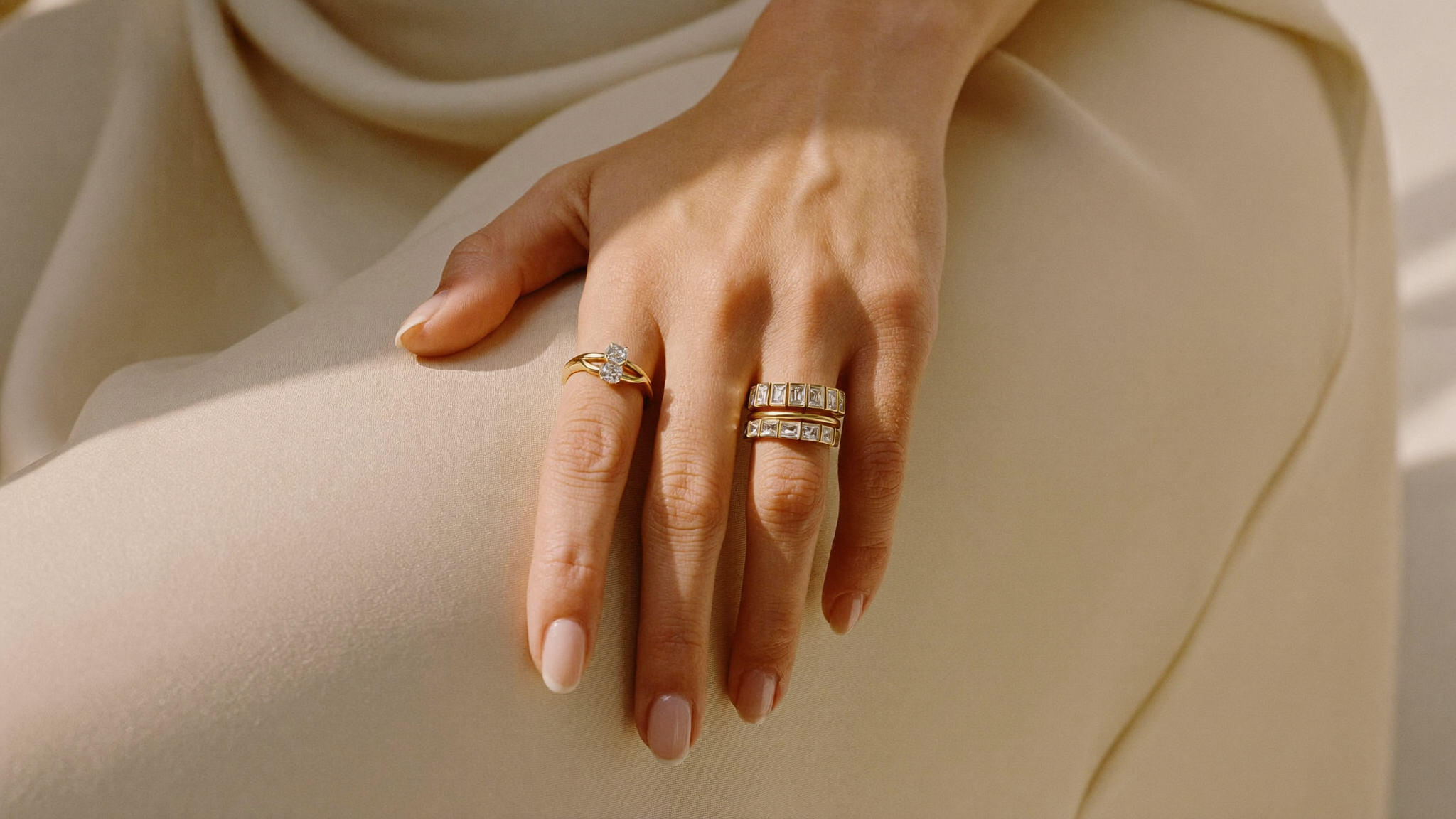 Close-up of stacked lab-grown diamond rings and gold bands on a woman's hand in natural light