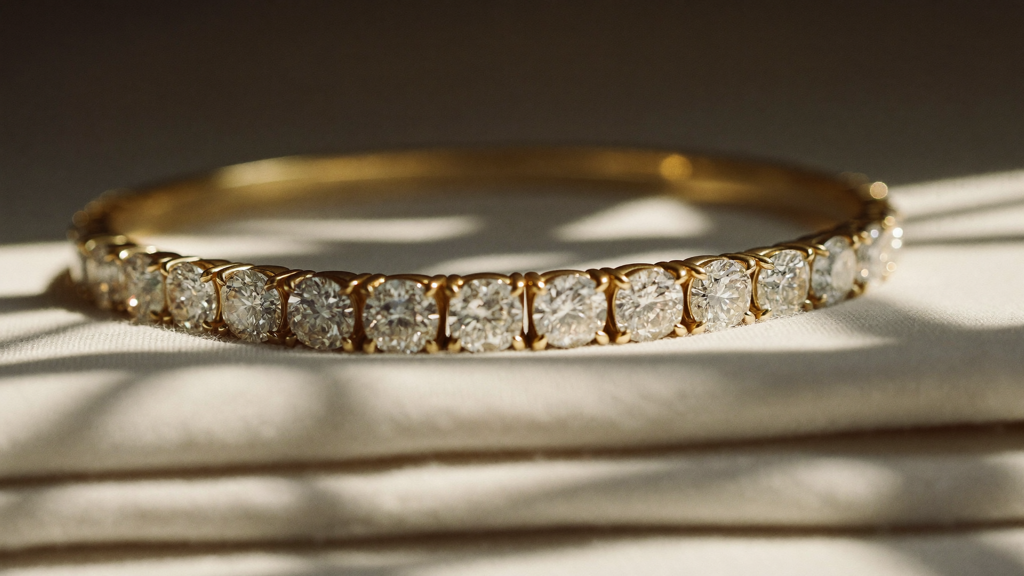 Lab grown diamond tennis bracelet in solid gold resting on cream linen in soft natural light