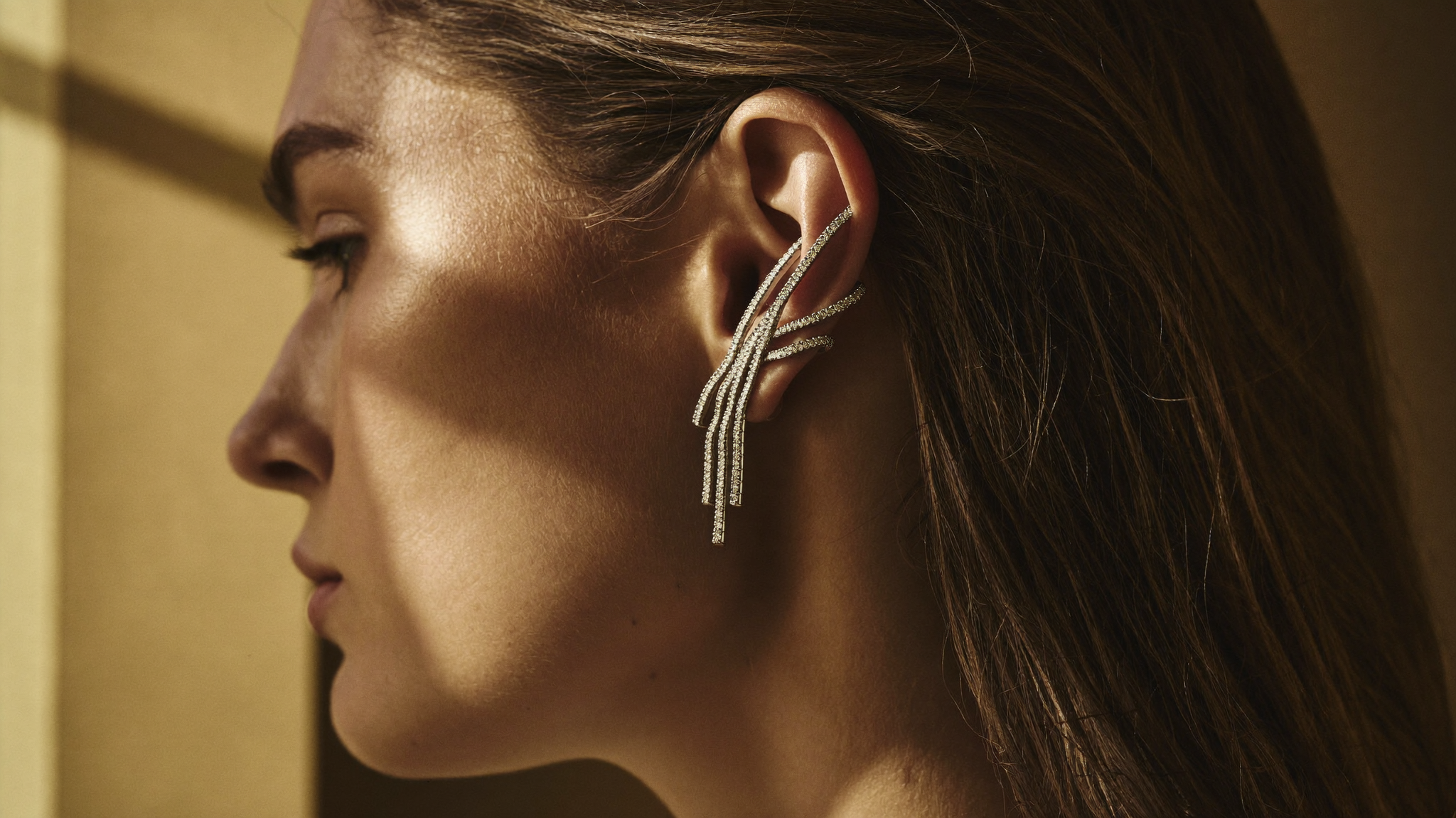 Sculptural diamond ear cuff climbing a model's upper ear in warm natural light