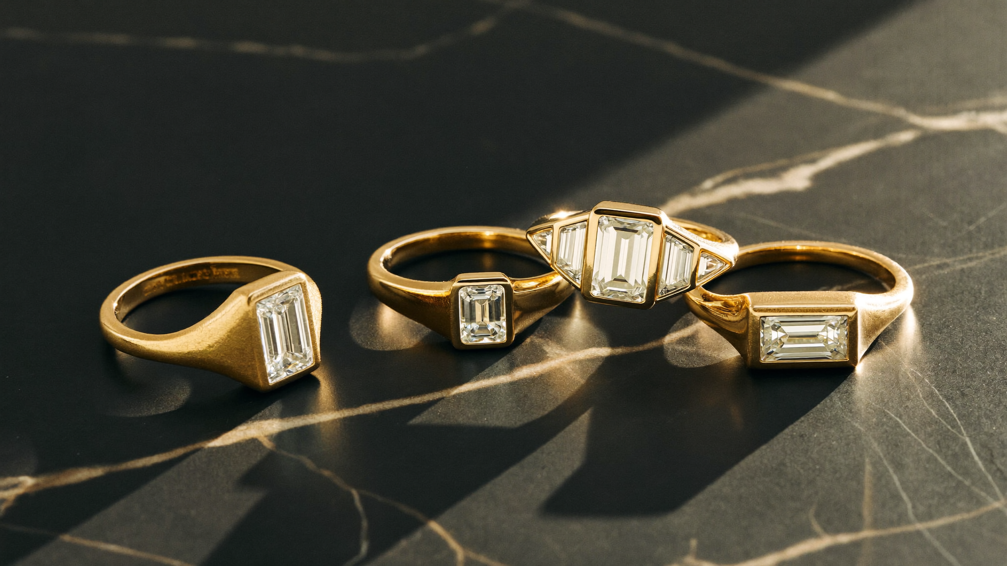 Close-up of geometric Art Deco diamond band rings with emerald-cut stones in gold on dark marble