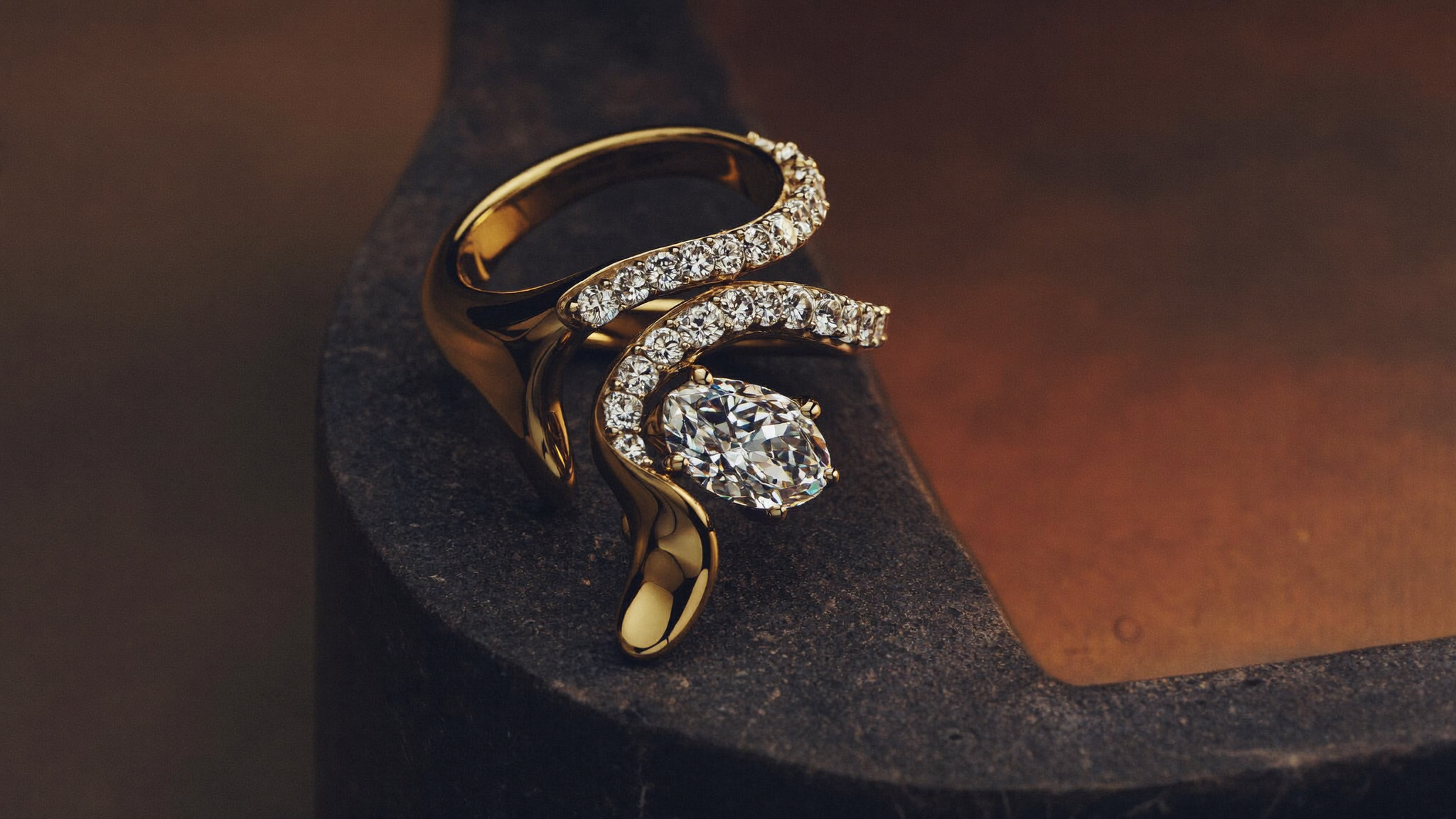 Sculptural bypass ring in gold with diamonds wrapping the finger