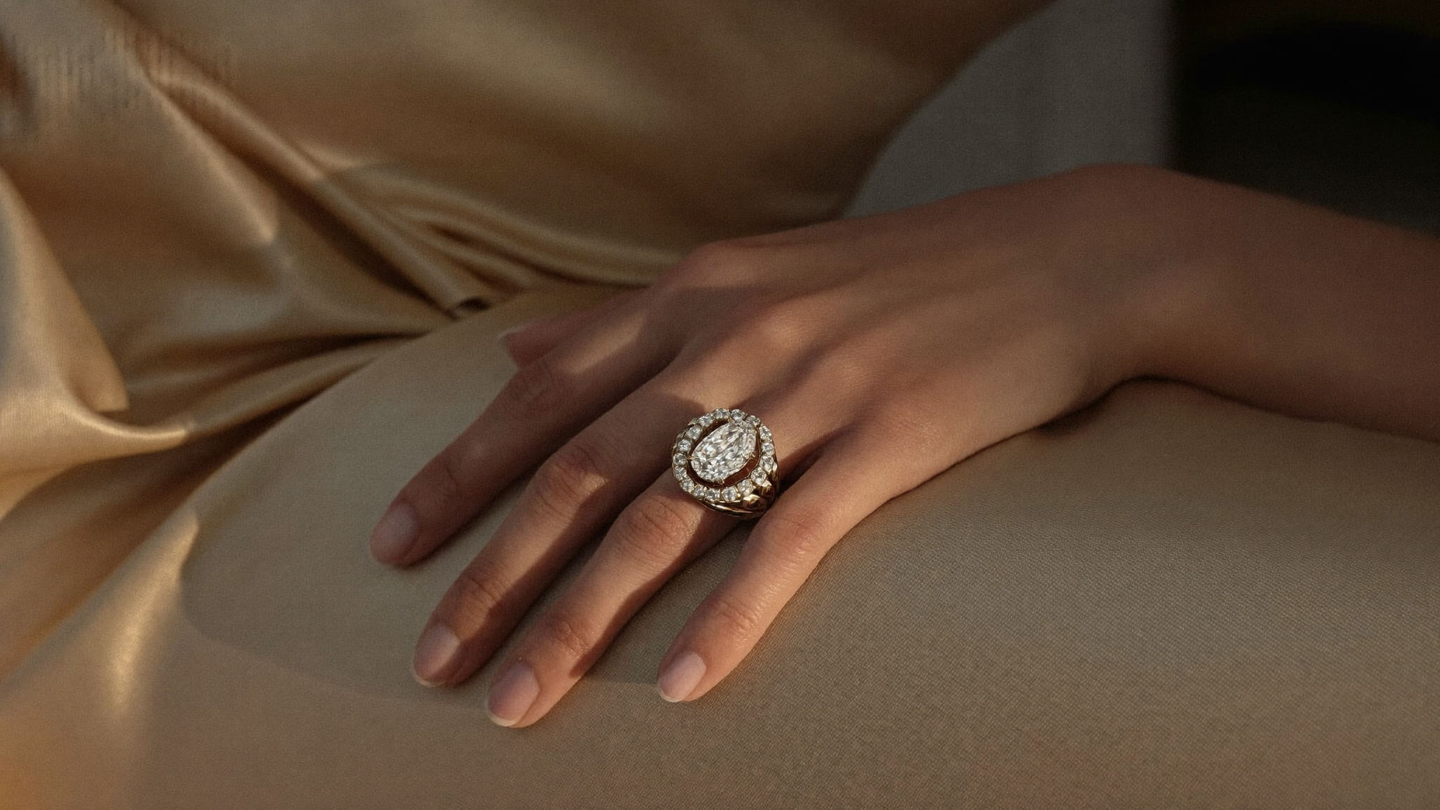 Bold sculptural diamond cocktail ring in solid gold on a hand against champagne silk