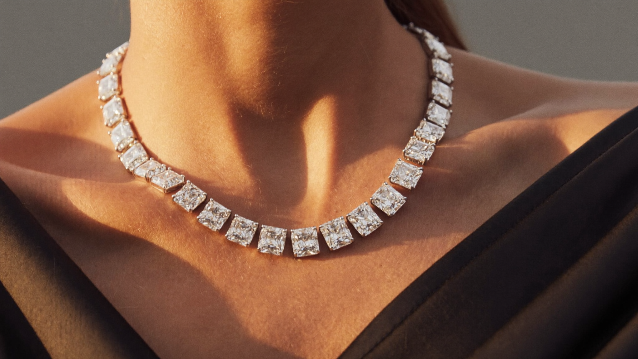 A diamond tennis necklace, a continuous rivière line of lab-grown diamonds, on a woman's collarbone in warm evening light